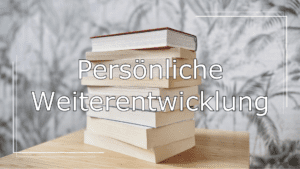 Im Hintergrund ein Stapel Bücher auf einem Holztisch. Im Vordergrund ein Schriftzug in Weiß mit schwarzer Umrandung. Der Schriftzug lautet: „Persönliche Weiterentwicklung“ und verweist auf die Kategorie der Leseempfehlungen.